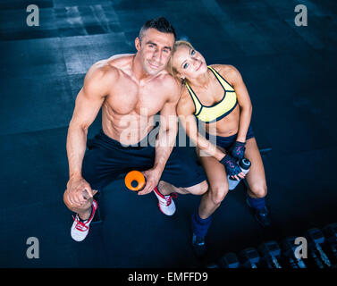 Souriant et heureux homme musclé femme sportive reposant sur l'audience à la salle de sport. Looking at camera Banque D'Images