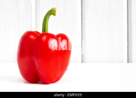 Rouge frais poivron (Capsicum) contre le bois blanc avec fond copyspace Banque D'Images