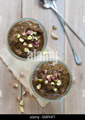 Photo verticale de matières organiques en bonne santé maison de l'avocat de la mousse au chocolat végétalien dans deux verres servis avec les pistaches. Banque D'Images