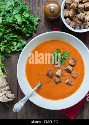 Photo verticale de soupe crème de tomate croûtons avec aliments complets dans un bol de soupe, plat servi avec du persil et du poivre. Banque D'Images