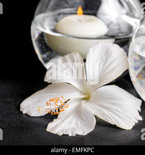 Spa concept de fleur d'hibiscus blanc et des bougies dans un vase avec de l'eau, gros plan Banque D'Images