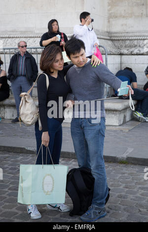 Young couple taking self portrait a l'aide d'un bâton selfies à Paris, France Banque D'Images