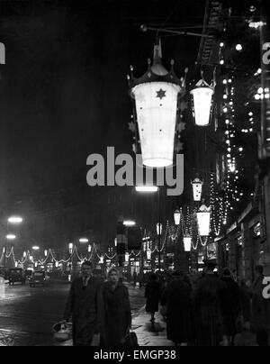 Shoppers passons en dessous pendaison illuminations sur Regent Street après les lumières de Noël ont été mis sous tension. 28 novembre 1958. Banque D'Images