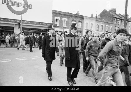 Gardez un oeil sur la police Leeds United partisans à l'arsenal du terrain en tant que fans arrivent à la station d'Arsenal avant le match. 29 janvier 1983. Banque D'Images