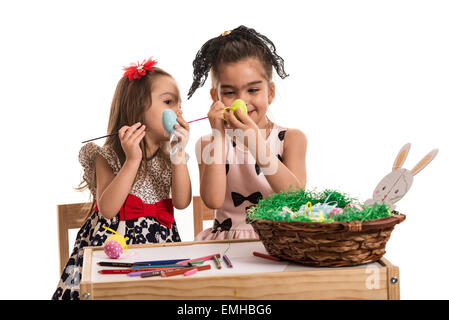 Deux sœurs créatif peinture oeufs de pâques et assis ensemble à table Banque D'Images