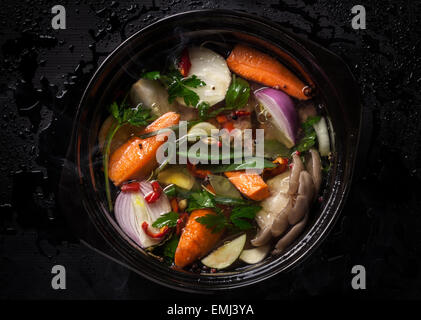 Soupe de légumes frais dans un pot sur fond noir Banque D'Images