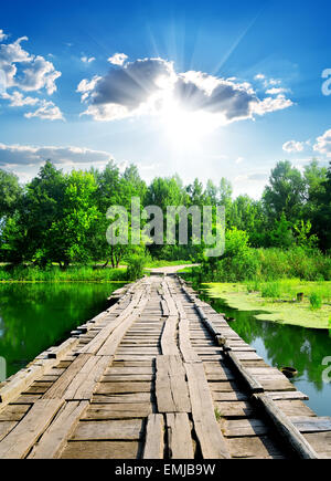 Plus de soleil pont de bois par rivière calme Banque D'Images