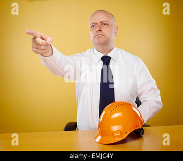 Ingénieur mâle au pouvoir, il porte une chemise blanche et cravate, le casque orange est sur la table Banque D'Images