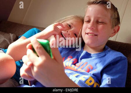 Un garçon et une fille rire et sourire tout en jouant sur un iPod tablet Banque D'Images