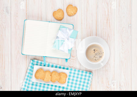 Café, biscuits en forme de coeur et le bloc-notes sur la table en bois blanc, avec copie espace Banque D'Images
