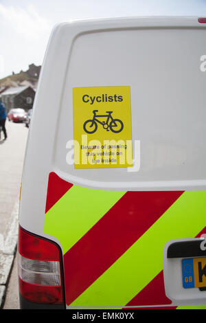 Un panneau d'avertissement sur fond blanc VW Transporter van 'cyclistes - méfiez-vous de ce véhicule qui passe à l'intérieur' pris sur le bord de la route Banque D'Images