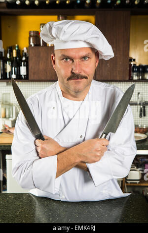 Mâle mature chef holding deux couteaux dans ses mains Banque D'Images