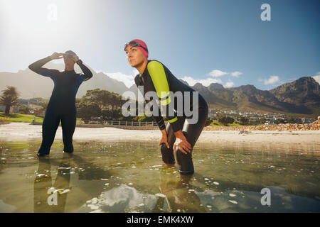 Déterminé les sportifs dans l'eau pour se préparer à la concurrence. Les triathlètes dans des combinaisons de la préparation pour le triathlon. Banque D'Images