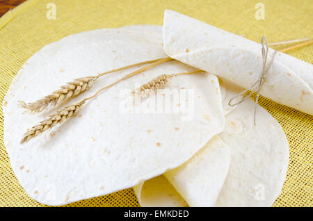 Paquet de tortillas et un bâton de blé sur une nappe jaune Banque D'Images