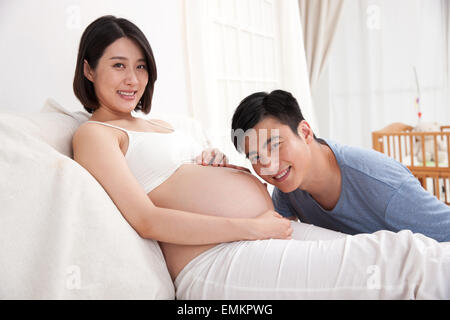 Le jeune père caressa le ventre enceinte pour écouter le fœtus Banque D'Images