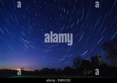 Astronomie - Star Trails au début du printemps au-dessus d'une église de village dans un petit village du nord du Yorkshire au Royaume-Uni. Banque D'Images