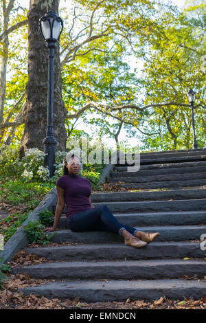 Une femme assise sur les marches de pierre dans un parc Banque D'Images