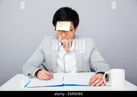 Businessman assis à la table et d'écrire quelque chose dans le document avec images Banque D'Images