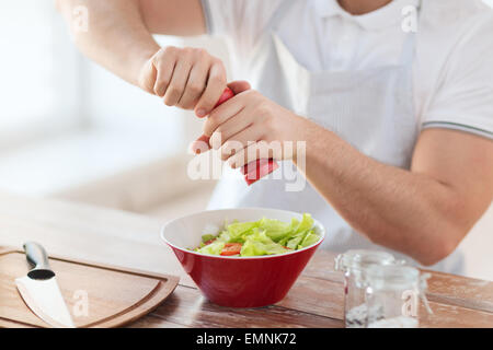 Les mains de l'assaisonnement dans un bol à salade Banque D'Images