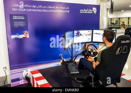 Abu Dhabi Emirats Arabes Unis Emirats Arabes Unis, aéroport international, AUH, terminal, portail, intérieur, arabe anglais, simulateur de voiture de course, homme hommes, drivi Banque D'Images