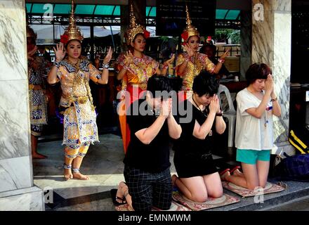 Bangkok, Thaïlande : les bouddhistes thaïlandais à genoux avec les mains jointes prière devant un groupe de danseuses à Khong Erawan Shrine Banque D'Images