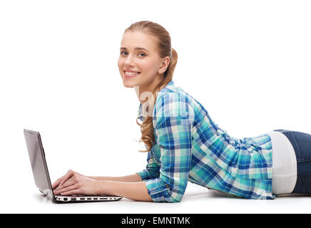 Smiling woman with laptop computer lying on floor Banque D'Images