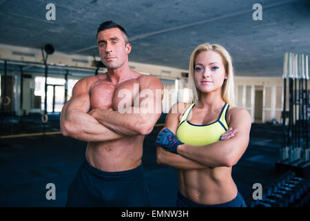 Le groupe d'un homme musclé et fitness femme debout les bras croisés dans la salle de sport crossfit Banque D'Images