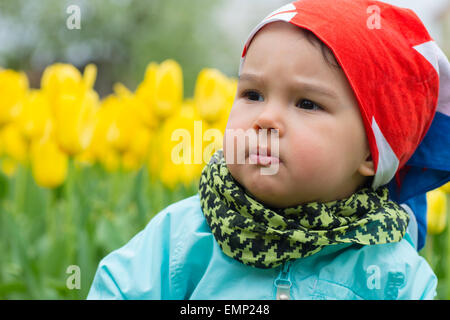 Belle petite fille avec un champ de tulipes en arrière-plan Banque D'Images