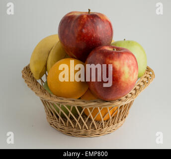 Panier rempli de bananes fraîches, vert et rouge des pommes et des oranges. Banque D'Images