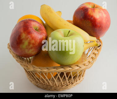 Panier rempli de bananes fraîches, vert et rouge des pommes et des oranges. Banque D'Images