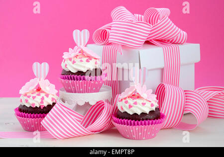 Heureuse Fête des mères rose et blanc cupcakes sur retro style cake stands et boîte-cadeau sur la table de bois blanc vintage. Banque D'Images