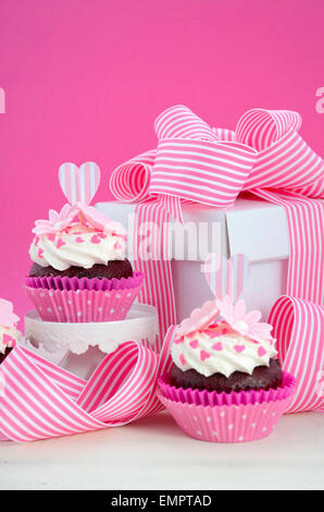 Heureuse Fête des mères rose et blanc cupcakes sur retro style cake stands et boîte-cadeau sur la table de bois blanc vintage. Banque D'Images