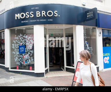Femme marche passé Moss Bros shop dans le centre d'Ipswich, Suffolk, Angleterre, RU Banque D'Images