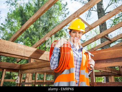 Female construction worker holding pipe et d'un marteau sur le site Banque D'Images