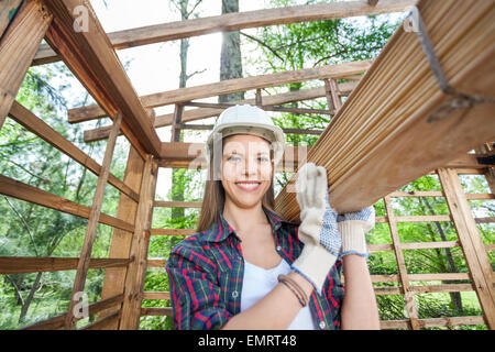 Happy female worker carrying wooden planks Banque D'Images