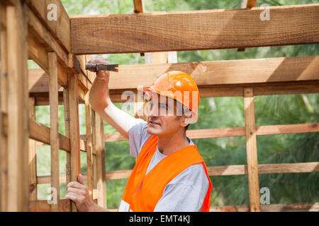 Martelage travailleur clou sur chalet en bois Banque D'Images