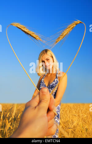 Belle jeune fille debout dans le champ de blé et en forme d'coeur bordure autour de son Banque D'Images