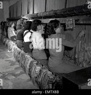 Historique Années 1950 coopératives de jeunes femelles assis sur un long banc fabrication de tapis à l'aide de métiers en bois, Palma de Majorque. Banque D'Images