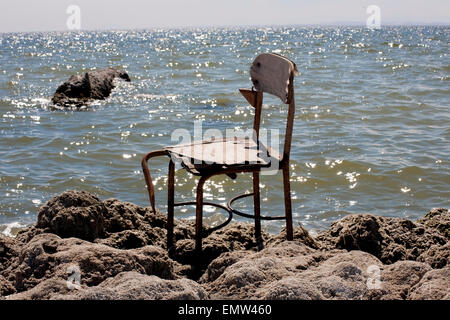 Un président siégeant seul sur la plage rocheuse de la Salton Sea en Californie du Sud. Banque D'Images