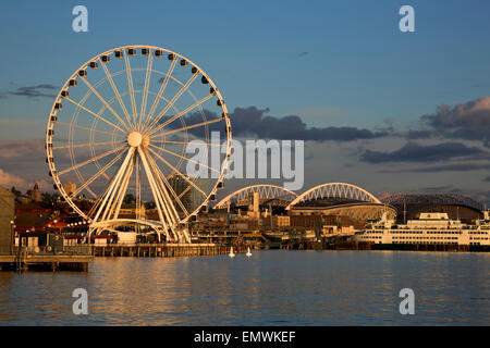 WASHINGTON - Elliott Bay et le front de mer de Seattle au coucher du soleil, avec la Grande Roue, cross-Sound, ferry et arènes sportives. Banque D'Images