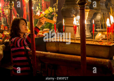 Femme chinoise l'encense herbal éclairage bâtons dans un monastère à Hong-Kong (Temple Man Mo) Banque D'Images