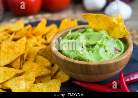 Guacamole au bol en bois avec des croustilles et des ingrédients Banque D'Images