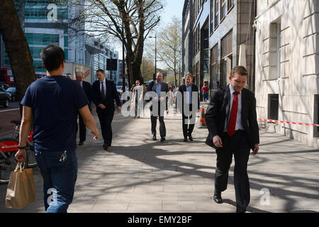 L'homme en jeans et T-shirt en passant devant les hommes en costumes sur la chaussée à Londres Banque D'Images