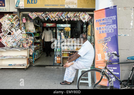 Un homme est assis à l'extérieur d'un petit dépanneur à Kuala Lumpur, Malaisie. Banque D'Images