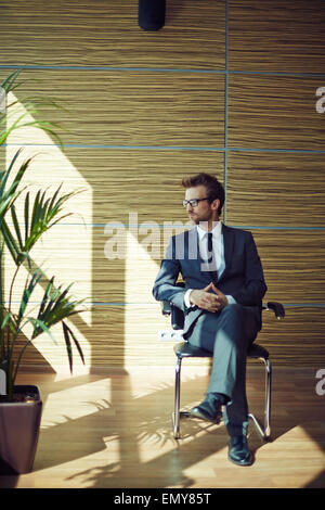 Elegant businessman sitting on chair Banque D'Images