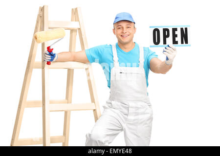 Jeune homme peintre dans un pyjama blanc et bleu shirt tenant un rouleau à peindre et un signe isolé sur fond blanc Banque D'Images