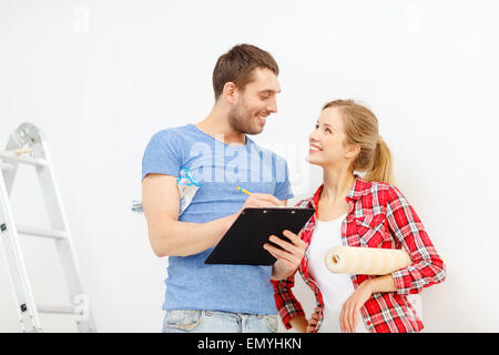 Smiling couple avec rouleau de papier peint et presse-papiers Banque D'Images