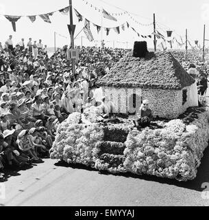 Le carnaval annuel de la Bataille de fleurs qui a eu lieu sur le canal de l'île de Jersey. Une maison faite de plantes à l'écran vu par des foules considérables. 5 août 1958. Banque D'Images