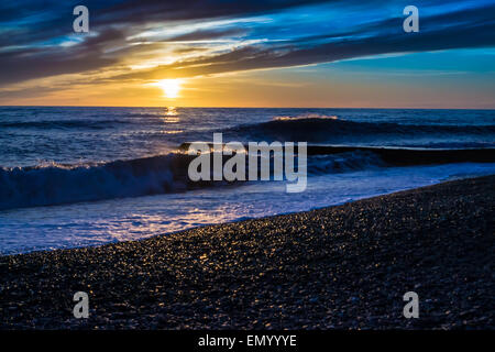 Coucher du soleil simple avec le fracas des vagues sur une plage de galets Banque D'Images