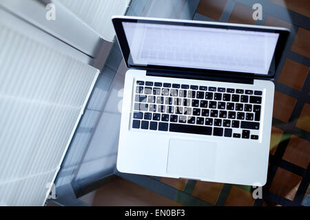 Vue du dessus de l'ordinateur portable sur une table en verre dans un intérieur moderne Banque D'Images